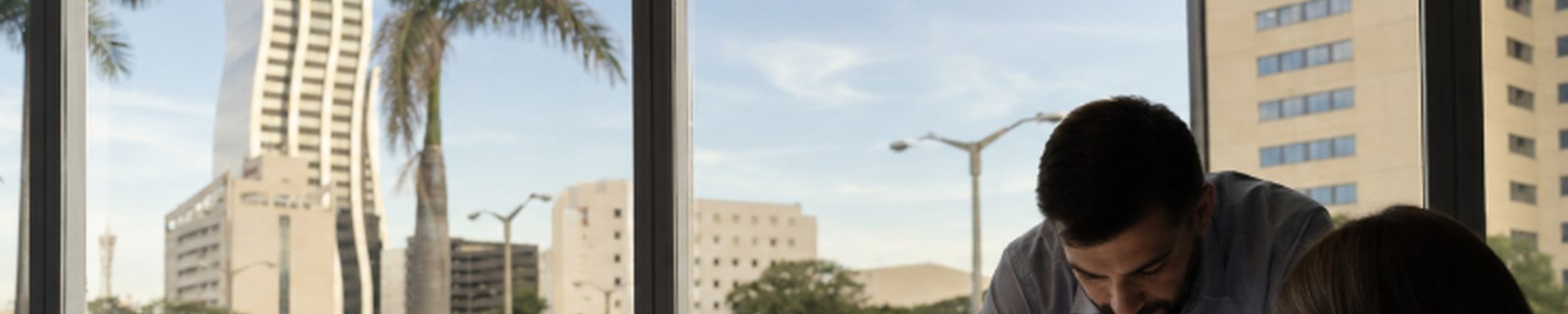 Reunión de asesoría profesional revisando documentos frente a una ventana con vista a Asunción